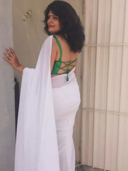 A classic white georgette saree paired with a green blouse featuring a stylish criss-cross back design. I focus on creating unique blouse designs to elevate any saree.