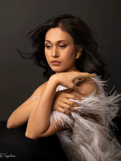 A more pensive and artistic shot from the same feathered look. The wind in her hair and her thoughtful expression create a portrait that feels like a painting.