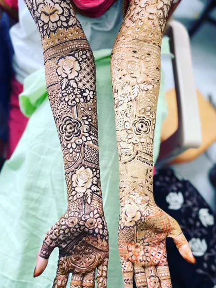 A before-and-after look at a floral design, showing the fresh paste on one hand and the developing stain on the other.