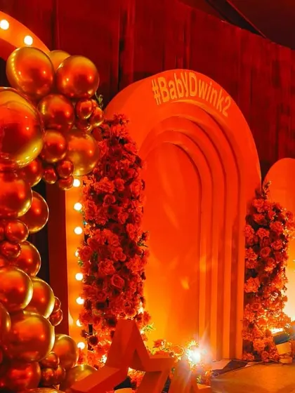 A closer view of the Bollywood themed party decor, highlighting the metallic red balloon garland and the lit marquee arch. This setup is designed to be a high impact photo opportunity for guests.