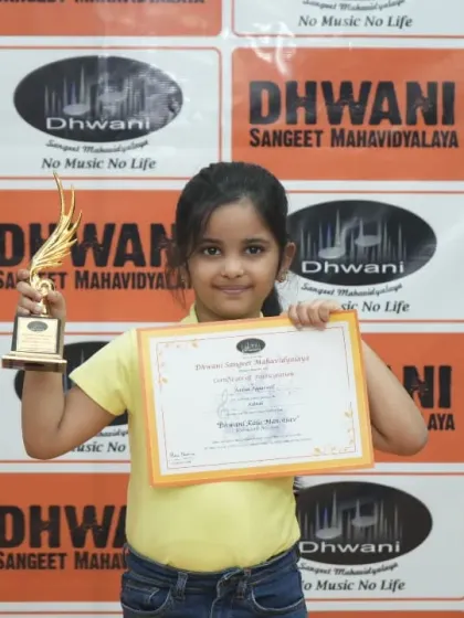A young girl proudly holds her certificate and trophy.