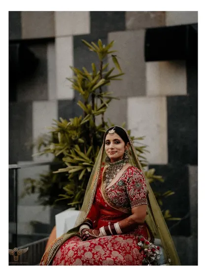 This portrait uses modern architectural elements as a backdrop. The clean lines of the tiled wall contrast beautifully with the bride's traditional red lehenga and soft pose.