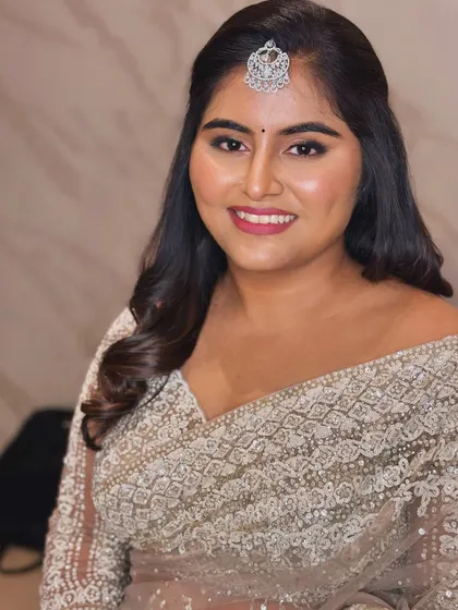 A smiling portrait of Niveditha, showing her radiant reception makeup.