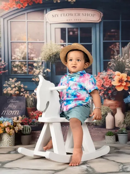 This little cowboy on his rocking horse is ready to ride into his second year. The flower shop theme adds a unique, gentle touch to the portrait.