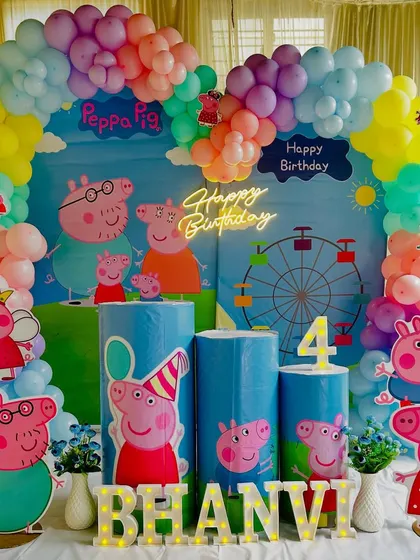 A cheerful Peppa Pig themed birthday party. We created this setup with a colorful balloon arch, custom printed plinths, and cutouts of Peppa and her family for a fun celebration.