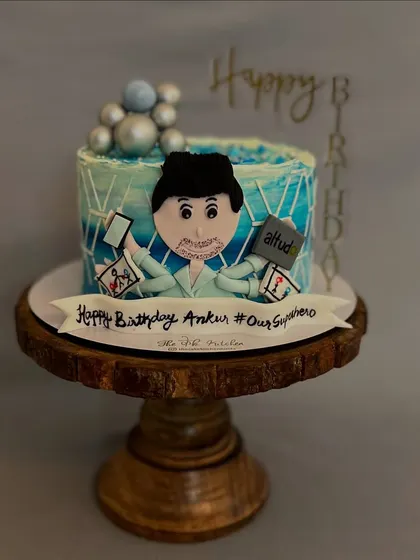 This "workaholic" cake was made for a superhero dad. It features a fondant caricature juggling a phone and laptop, surrounded by his favorite things.