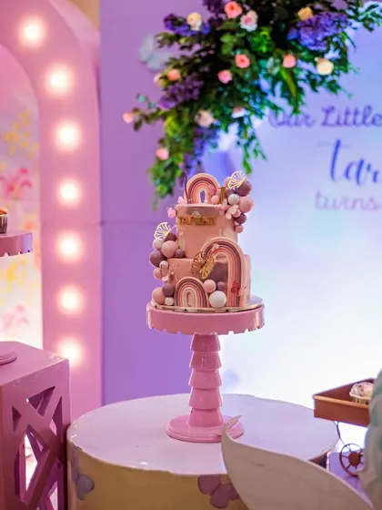 A stunning, multi-tiered cake adorned with rainbows and clouds, fitting perfectly into a dreamy, magical theme. The cake is often the centerpiece of the dessert table, and I ensure it's beautifully displayed.