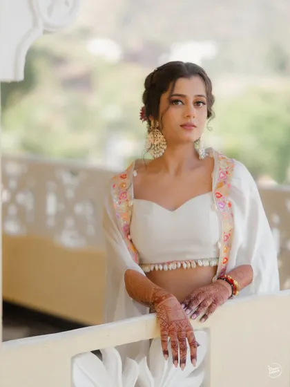 A beautiful portrait of the bride in her elegant white Haldi outfit, showcasing her intricate henna and stunning jewelry.