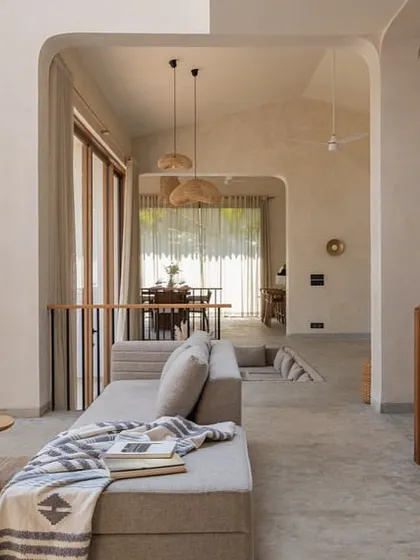 In the House of Basho, we opened up the existing structure to create softer edges and better flow. This view from the living area looks through arched openings towards the dining space, showcasing the home's light and airy feel.