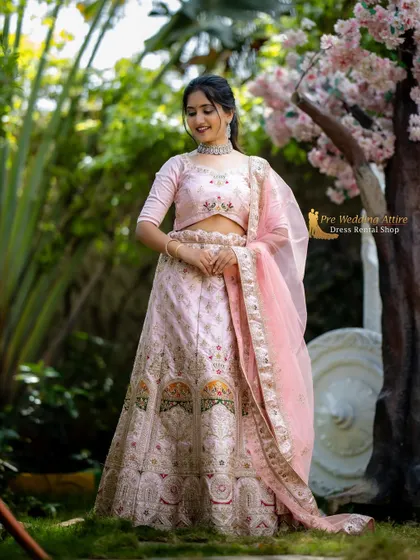 A delicate pink lehenga with floral embroidery and a matching sheer dupatta. This outfit is perfect for a soft, romantic theme in a garden or park setting.