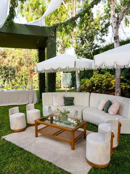 A comfortable and stylish lounge area created for an outdoor anniversary party. The plush white sectional sofa, patterned rug, and elegant furniture invite guests to relax and mingle.