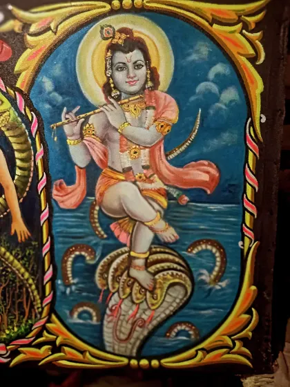 A close-up of the Lord Krishna painting, showing the detail in his expression, ornaments, and the texture of the water.