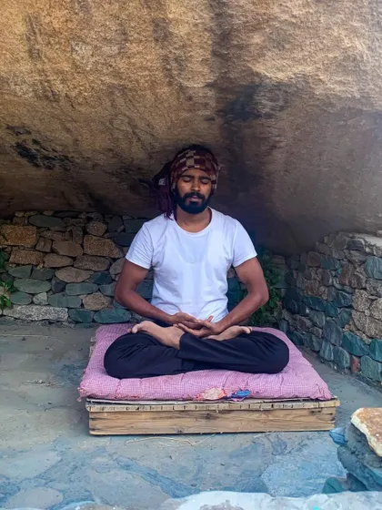 Meditating on a simple wooden platform in a cave, a moment of deep, rustic practice.
