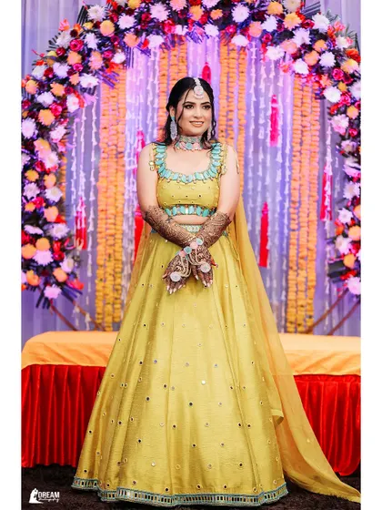 A classic portrait of bride Harshna in her yellow Mehndi outfit, her smile radiating happiness against the festive decor.