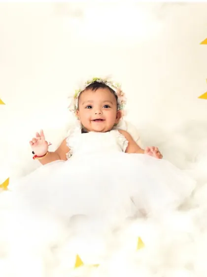 A happy little angel with a bright smile. The soft clouds and golden stars create a warm and joyful atmosphere.