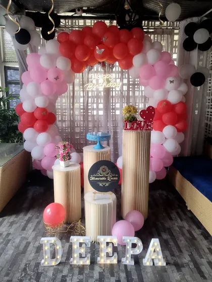 A birthday setup with a pink, white, and red balloon ring in a restaurant setting.