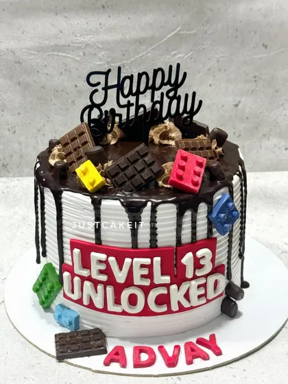 A fun "Level 13 Unlocked" cake perfect for a teenage gamer. This design combines a chocolate drip with edible Lego blocks and a bold gaming-themed message.