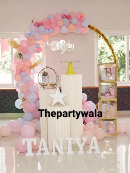 A sweet baby shower setup with a pastel pink balloon arch and 'BABY' blocks.