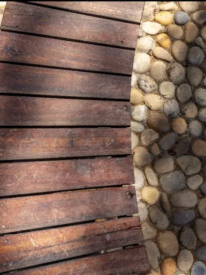 The texture of the placemaking project, showing the contrast between smooth, reclaimed wood and natural river stones. Every material choice is intentional, designed to create a space that is both tactile and visually integrated with its surroundings.