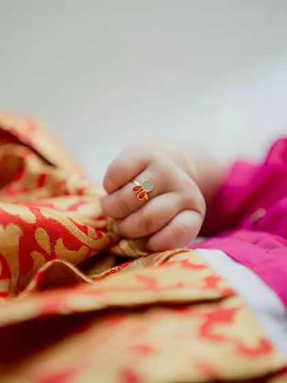 Another tiny detail from the naming ceremony. The baby's little hand, adorned with a delicate ring, resting on her vibrant silk outfit, tells a story of tradition and love.