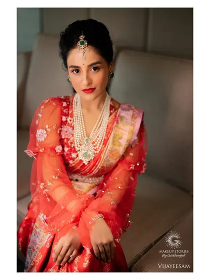 A beautiful portrait of Krishna. The makeup focuses on a classic red lip and clean, elegant eye makeup, paired with a modern hairstyle for a sophisticated fusion look.