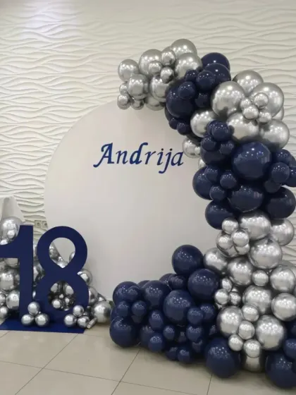 A personalized 18th birthday with a custom name backdrop and a balloon arch in navy blue and chrome silver.