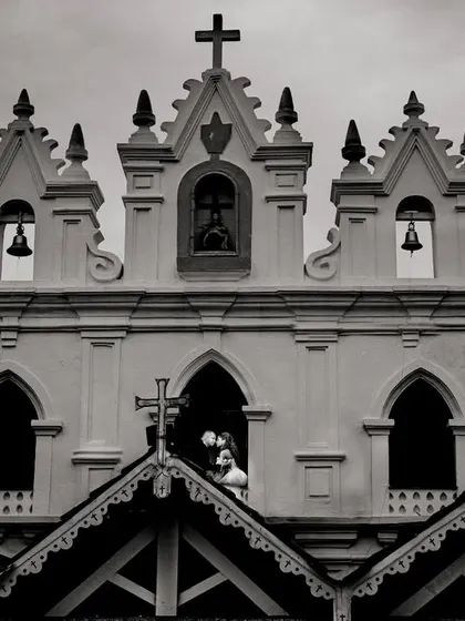 A creative composition framing the couple's kiss within a church window. This black and white shot uses the building's architecture to create a unique, layered portrait that feels both grand and intimate.