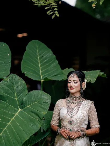 An elegant bride in a white and silver saree, her look completed by the detailed mehendi art peeking through. The henna adds a traditional touch to her modern and sophisticated style.