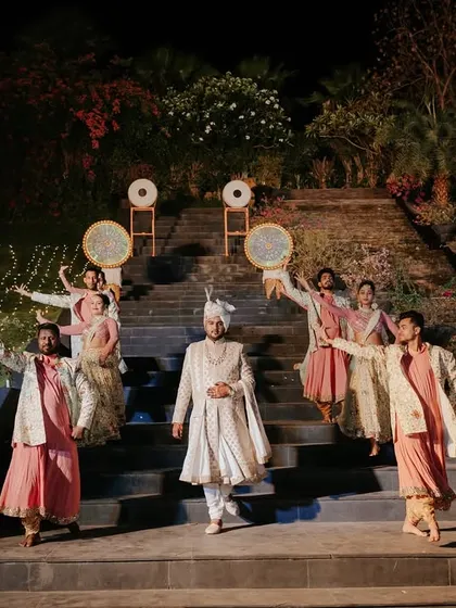 The groom makes his grand entrance for the Varmala, flanked by performers. The anticipation builds on the magnificent stone steps, setting the stage for a truly memorable union.