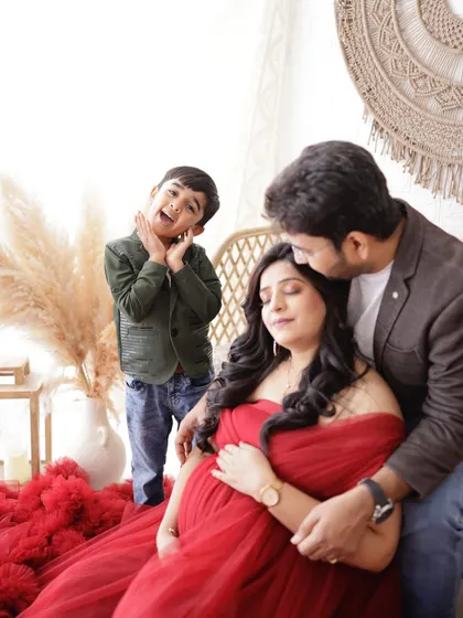 A candid and joyful family moment. Big brother's playful expression is priceless as he shares the spotlight with his expecting parents.