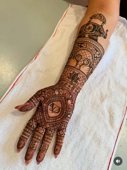 A beautiful example of incorporating initials. This single-arm design features the couple's initials 'VC' in a heart shape on the palm, with swan and elephant motifs on the arm.