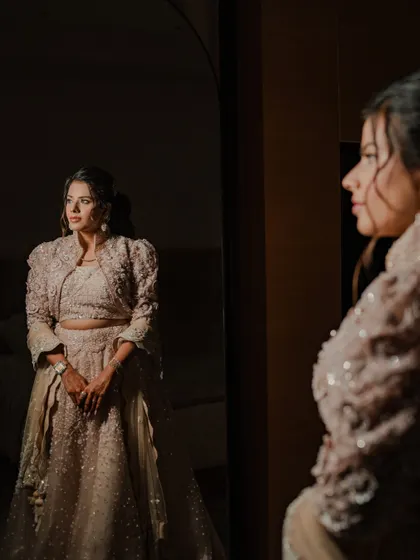 A moment of reflection. The bride looks at her reflection in the mirror, a thoughtful and beautifully lit portrait capturing the moments before her engagement.