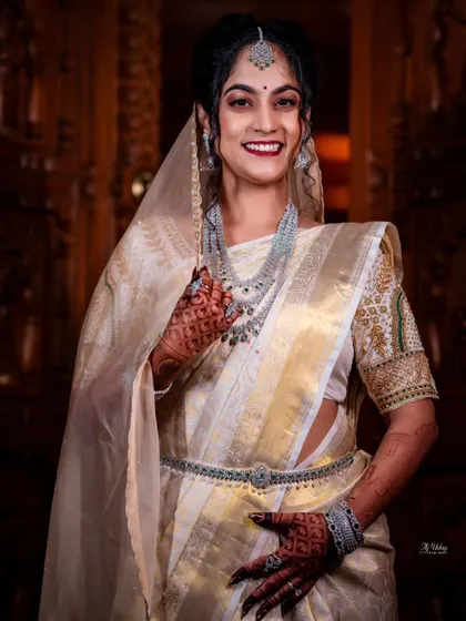 For her reception, this Iyer bride chose a stunning off-white and gold saree draped in a Kannadiga style. The addition of a sheer veil and diamond jewelry created a look of modern royalty.