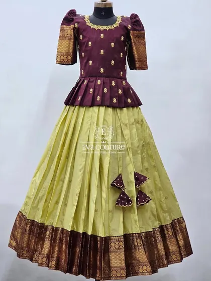 A mannequin view of the maroon and lime green pattu lehenga. The peplum top and puff sleeves add a modern touch to the classic color combination.