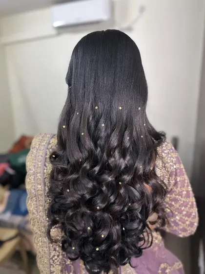 A simple yet stunning reception hairstyle with open curls, dotted with tiny pearl accessories for a subtle, starry effect.