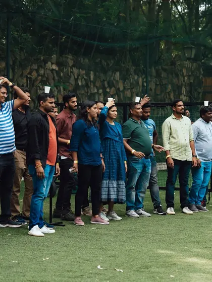 A lineup of team members, each balancing a cup on their head, ready to take on the Pyramid Builder challenge.