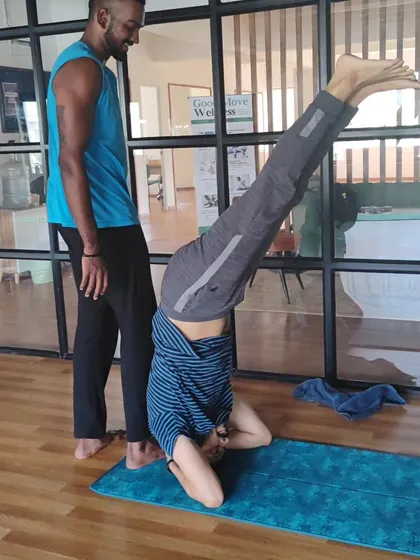 A student practicing a headstand with the support and guidance of another practitioner during the workshop. We learn and grow together.