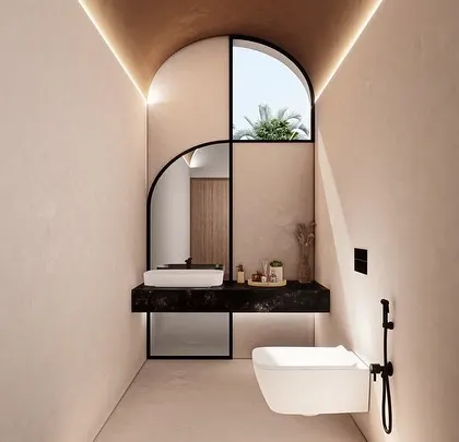 The powder room in a Vagator Villa uses dramatic lighting and a custom arched mirror to create a memorable space. The design plays with form and reflection within a narrow footprint.