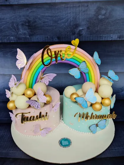 Another beautiful twinning cake design for a first birthday. These two cakes, one pink and one blue, are united by a rainbow and adorned with delicate butterflies.
