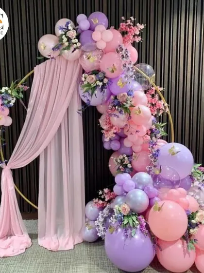 A beautiful circular arch decorated with purple and pink balloons, soft draping, and floral accents. This makes a perfect photo backdrop for a birthday or baby shower.