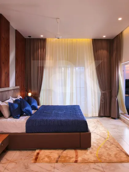 This luxurious bedroom exudes timeless elegance with its refined decor. The rich satin drapes frame a large window, offering a beautiful view and creating a serene haven for rest.