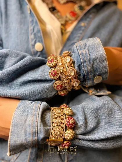 A close-up on the stacked bangles from our Navratna-inspired collection, featuring intricate settings with rubies and polki diamonds.