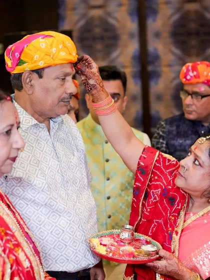 A beautiful moment during a puja, where a woman applies a tilak to a man's forehead. The photo captures the seriousness and beauty of the tradition.