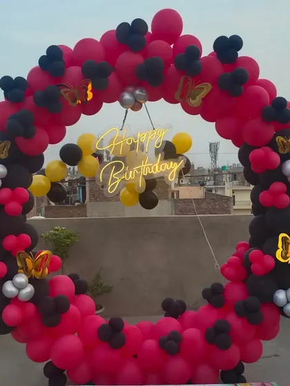A striking red and black balloon ring for a rooftop birthday party. The butterfly accents add a touch of elegance to the bold color combination.