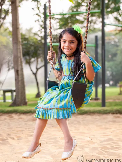 A young girl enjoys a ride on a swing in the park. Her happy, carefree expression is what makes outdoor photoshoots so special and authentic.