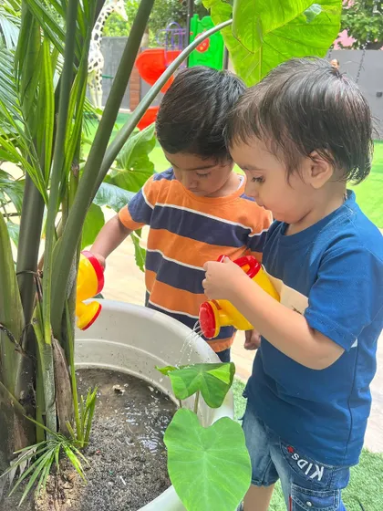 A pair of friends carefully watering a plant together. We provide opportunities for children to connect with nature and learn through hands-on experiences.
