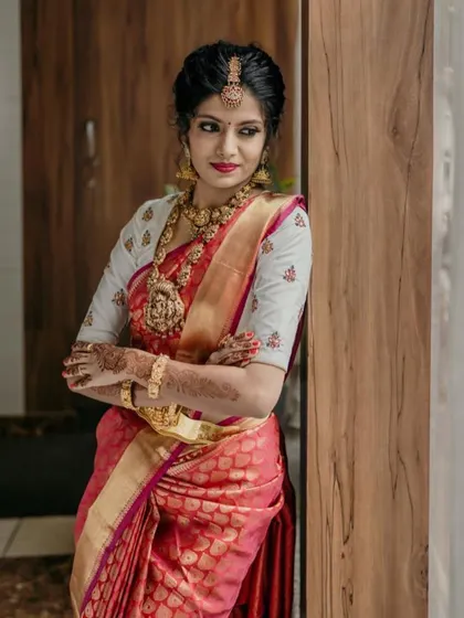 The bride posing gracefully, showing the beautiful drape of her red silk saree and the fit of her custom blouse.