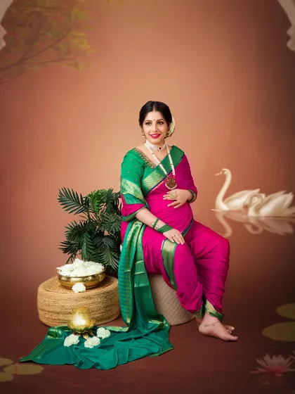 A joyful and classic portrait in a traditional 'nauvari' saree. The props and setting are designed to evoke a sense of timeless Indian heritage.