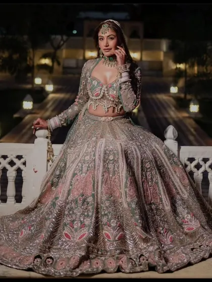 For the bride who wants to make a statement, we offer exclusive couture pieces for rent. This designer lehenga features a modern corset-style blouse with pearl detailing and a unique pastel floral skirt, perfect for a destination wedding or a grand reception.