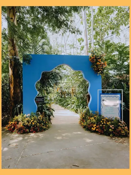A bold and beautiful entrance arch in a striking blue, framed by colorful marigolds, setting a playful and welcoming tone for a summer Haldi.